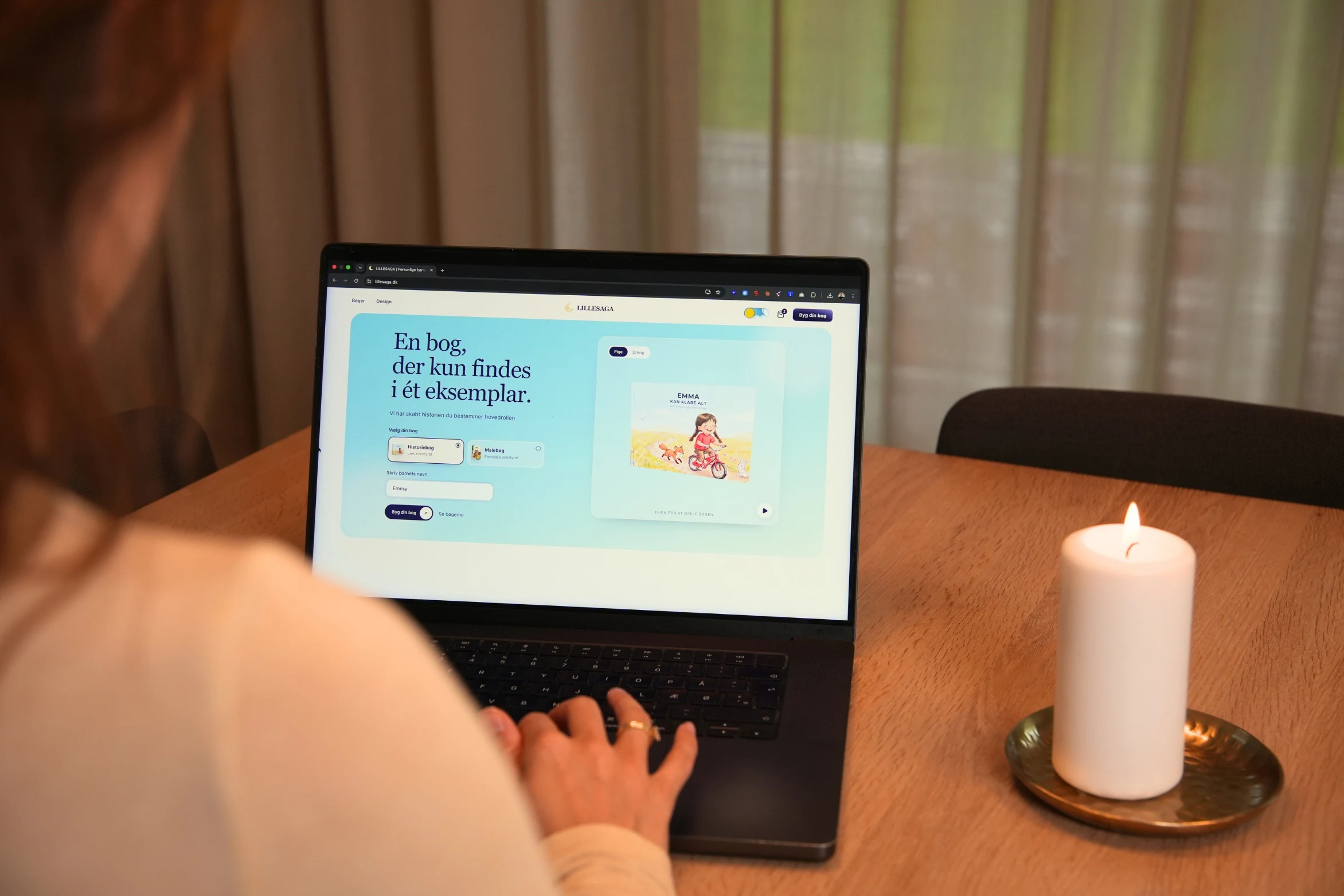 En forælder designer en personlig bog på sin bærbare computer ved spisebordet.